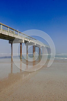 Long wooden pier stretching out to a foggy ocean