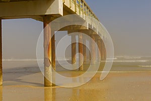 Long wooden pier stretching out to a foggy ocean horizon