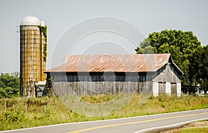Long, Wooden Rustic Barn with Silo on a Country Road