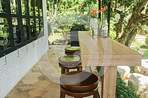 Long wooden table with fresh flower vase and chairs at the house garden
