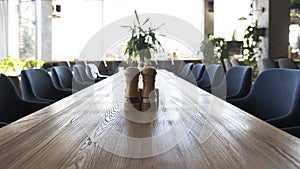 Long wooden table with salt and pepper, interior of modern restaurant