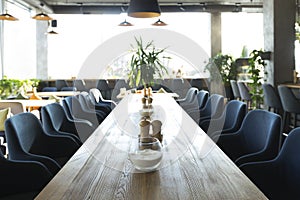 Long wooden table with soft chairs in cozy cafe
