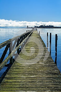 Long wooden weathered wharf extending far out into a lake