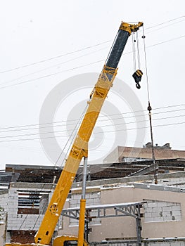 Long yellow crane jib near house under construction