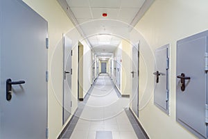 Long yellow hallway with grey metal doors and floor