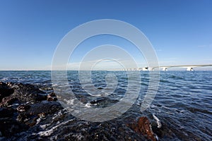 Long Zeeland Bridge, deep blue water with buoy, blue sky with white clouds