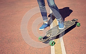 Longboard girl on the street at beautiful summer day. Toned in warm colors.