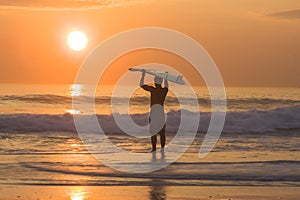 Longboard surfer silhouette at golden sunset