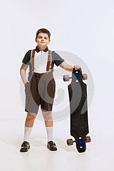 Longboarder. Studio shot of little boy, preschool age kid wearing retro style clothes isolated over white background