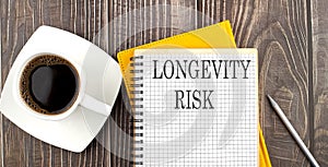 LONGEVITY RISK text on the notebook with coffee on wooden background