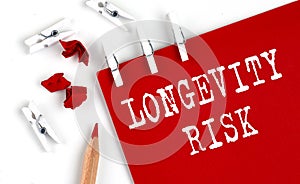 LONGEVITY RISK text on red paper with office tools on the white background