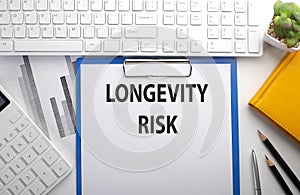 LONGEVITY RISK written on the paper with keyboard, chart, calculator and notebook