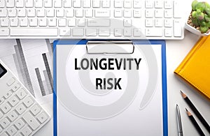 LONGEVITY RISK written on paper with keyboard, chart, calculator and notebook