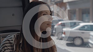 A longhaired girl sitting in a bus and looking outside the window