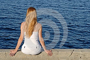 Longhaired girl sitting by the sea