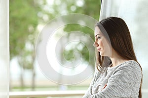 Longing woman looking through window at home