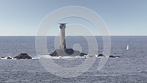 Longships Lighthouse in the Atlantic at Lands End in Cornwall. A sailing yacht is nearby.