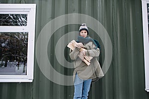 Longshot portrait of a woman in snowy winter clothes holding logs in hands