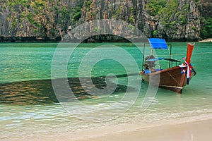 Longtail boat anchored at Maya Bay next to school of fish on Phi