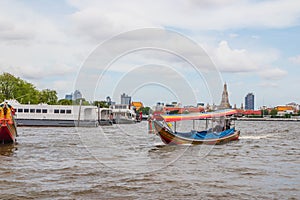 A longtail boat, the Chao Phraya River, the Thai royal first class Temple Wat Arun and the Cityscape of Bangkok Thailand Southeast