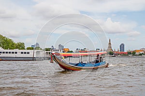 A longtail boat, the Chao Phraya River, the Thai royal first class Temple Wat Arun and the Cityscape of Bangkok Thailand Southeast