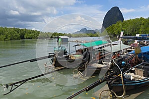 Longtail boat with coastal fishing village in phang - nga