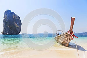 Longtail boat mooring on the tropical beach with limestone rock at Poda island