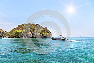 Longtail boat sailing on the tropical andaman sea with small limestone island background