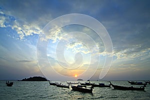 Longtail boats on seashore at sunrise