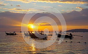 Longtail boats on seashore at sunset