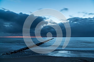 Longtime exposure of the ocean with clouds and orange light at the horizon