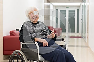 Lonley elderly 95 years old woman sitting at the wheelchair using modern mobile phone. photo