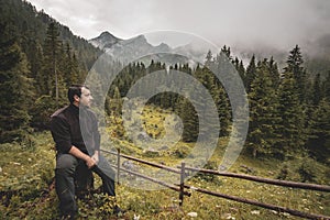 Lonley man in front of a remote mountainscape on a rainy day