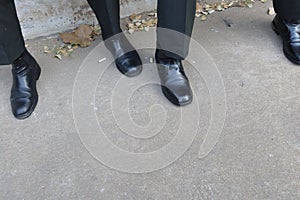 Look above the legs of a man wearing black slacks wearing leather shoes. photo