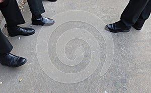 Look above the legs of a man wearing black slacks wearing leather shoes. photo
