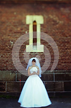 A look from afar on a bride standing under a small window