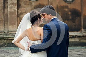 A look from behind on a groom hugging delicate bride`s waist