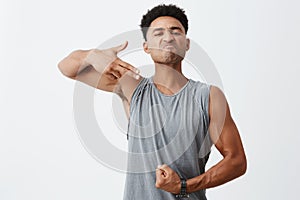 Look at this body. Portrait of young dark-skinned serious man with afro hairstyle showing gun gesture with hand