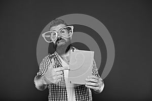 Look at this book. Bearded man in party glasses pointing at lesson book. Study nerd holding book. Book nerd wearing