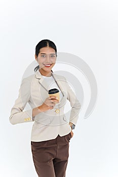 Look at the camera for a portrait of a young businesswoman posing with paper cup of coffee or tea, isolated on white background.