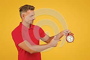 Look at clock. Handsome man point finger at alarm clock. Check current time. Countdown and deadline. Punctuality and