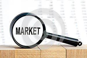 Look closely and MARKET with a magnifying glass , business concept image with soft focus background