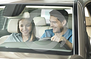 Look at this console! Beautiful young couple sitting at the front seat of the car checking out the side panel