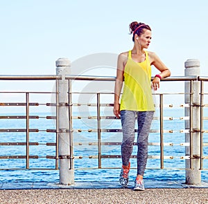 Young woman in fitness outfit looking aside at embankment