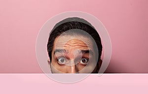 Look half face on a pink background. A surprised look on a man`s face.