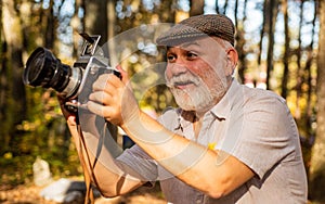 Look at this. Happy pensioner hold camera in nature. professional photographer with camera. The photographer hold DSLR