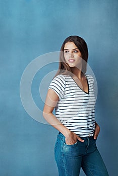 Look how far youve come. Studio shot of an attractive young woman looking thoughtful against a blue background.