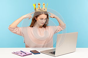 Look, I am the best! Proud egoistic narcissistic woman pointing crown on head and talking on video call