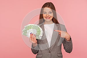 Look, I am rich! Portrait of millionaire, elegant wealthy woman in suit holding euro banknotes and smiling