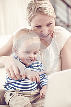 Look mommy. An attractive young mother showing her curious baby a touchscreen tablet.